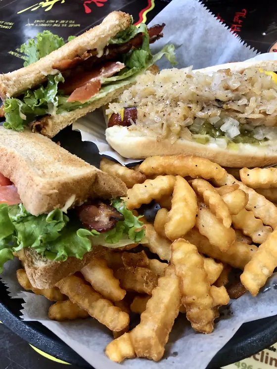 A BLT on toast, a loaded hot dog and crinkle-cut fries in a paper-lined basket