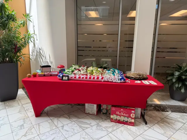 A catering table with a red tablecloth set up in an office lobby