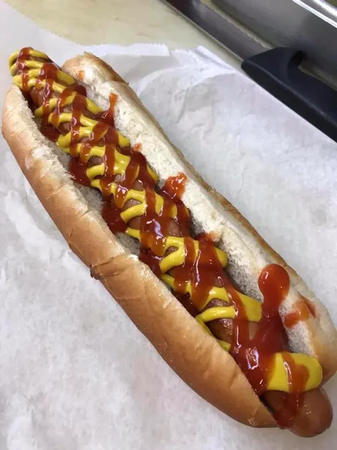 A footlong hot dog with ketchup and mustard on deli paper