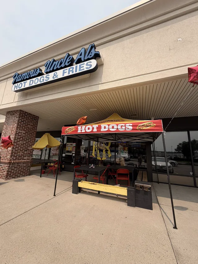 The Famous Uncle Al's storefront: a blue Hot Dogs & Fries sign, a red Hot Dogs canopy and outdoor tables